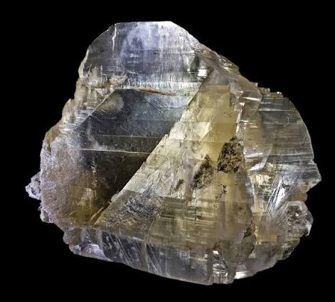 Large raw Gypsum crystal displaying glassy transparency with golden-grey tones and characteristic stepped cleavage faces against a black background