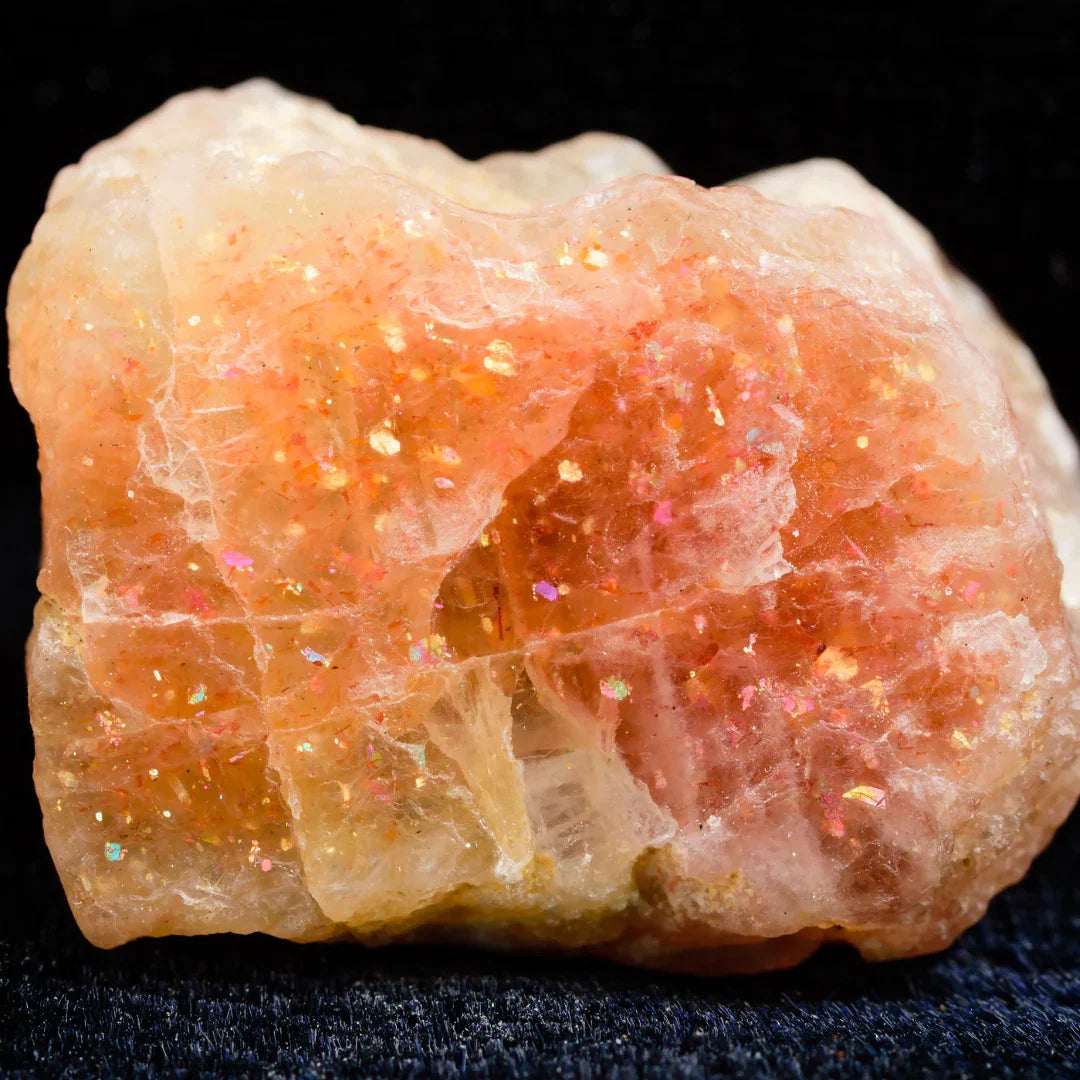 Natural peach and orange Sunstone specimen with glittering aventurescence on a black background